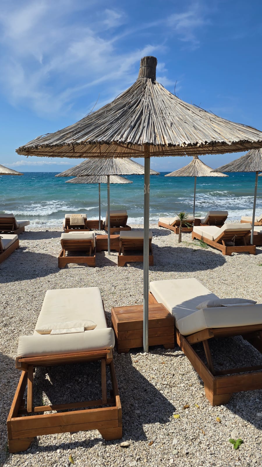 Straw umbrella and sunbeds over turquoise water